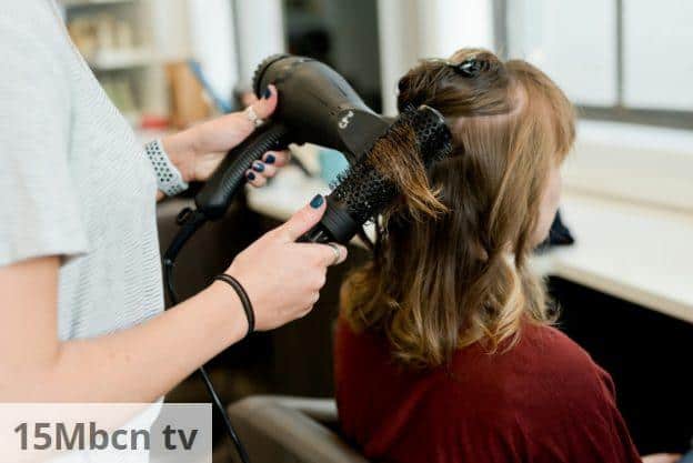 woman in red long sleeve shirt holding hair blower