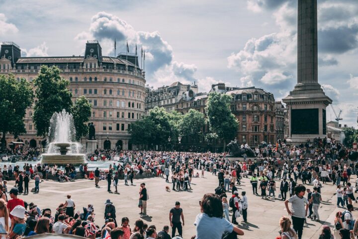 Multitud en una plaza de una gran ciudad bajo un cielo con nubes